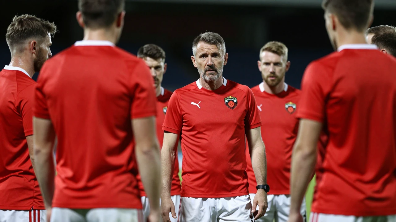 A waist-up shot of a middle-aged Oldham Athletic coach, wearing a bright red away kit and white shorts, intense focus in...