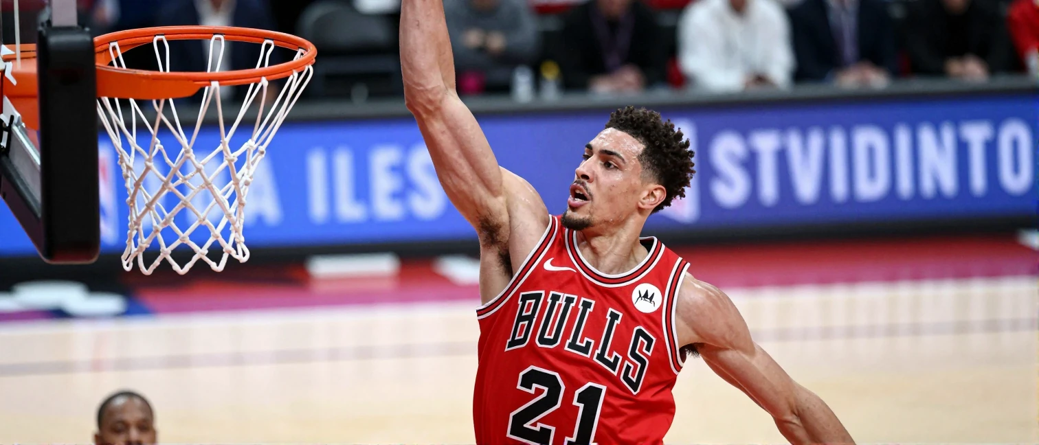 A high-angle editorial shot of a Chicago Bulls player in plain red jersey, mid-air executing a powerful one-handed slam dunk