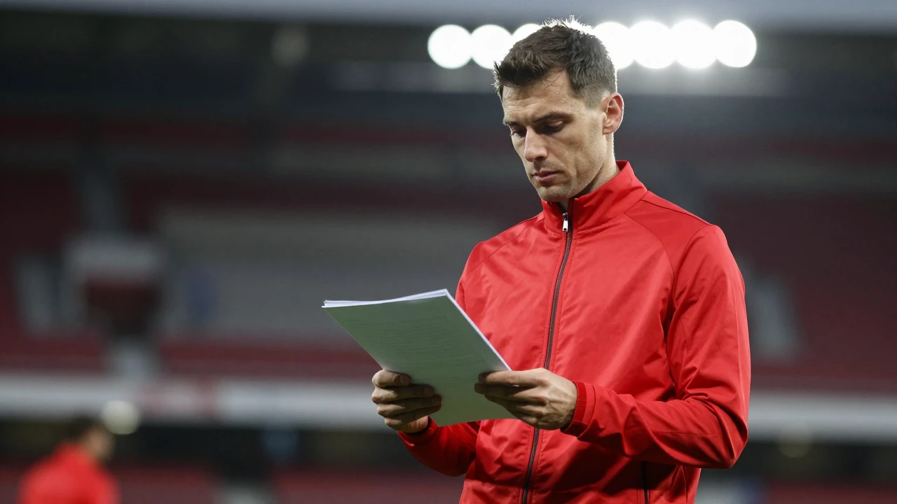 A mid-30s anonymous Ajax staff member, waist-up, wearing a solid red training jacket, looking thoughtfully at a transfer...