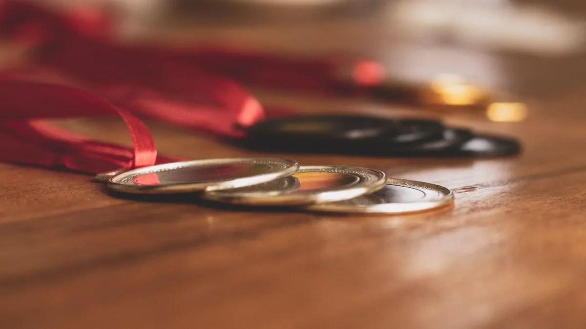 Other Fields: Close-up view of medals on a wooden table, showcasing bronze, silver, and gold awards. Awards