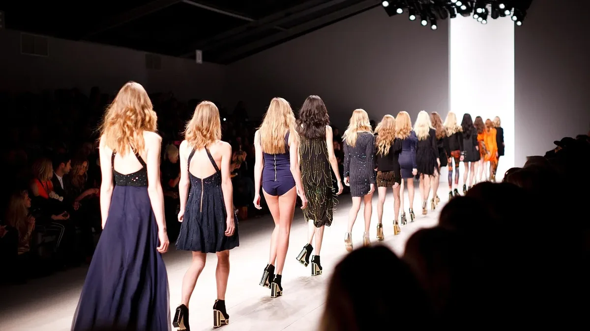 Film: A group of women walking down a runway in a fashion show, with an audience watching from the side.