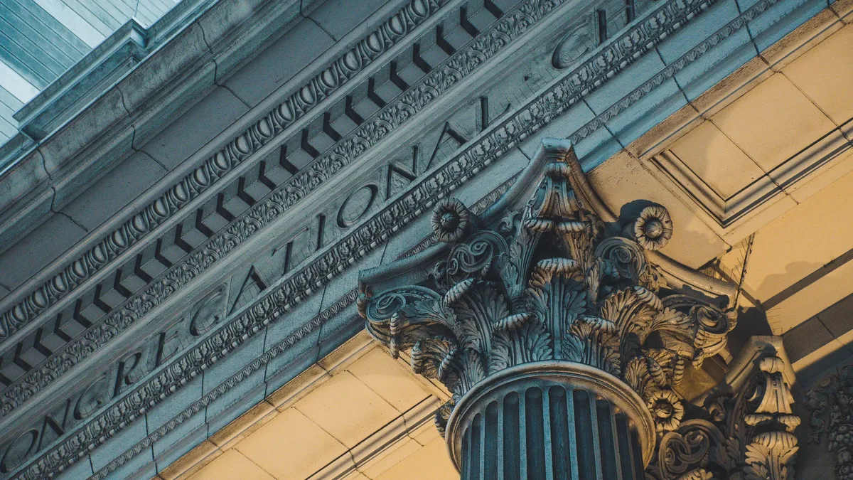 Policy Areas: A close-up view of the top of a column and the facade of a building with ornate architectural details.