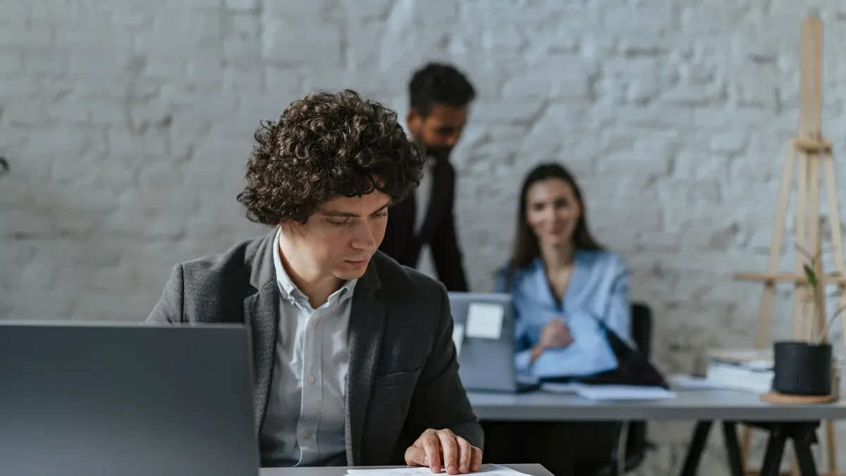 Business professionals working together in a modern office setting with focus on curly-haired man reviewing documents