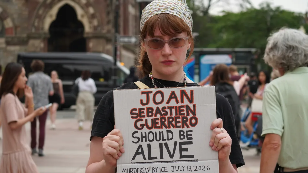 A protester holds a hand-lettered cardboard sign memorializing Joan Sebastian Guerrero, the 26-year-old Colombian man