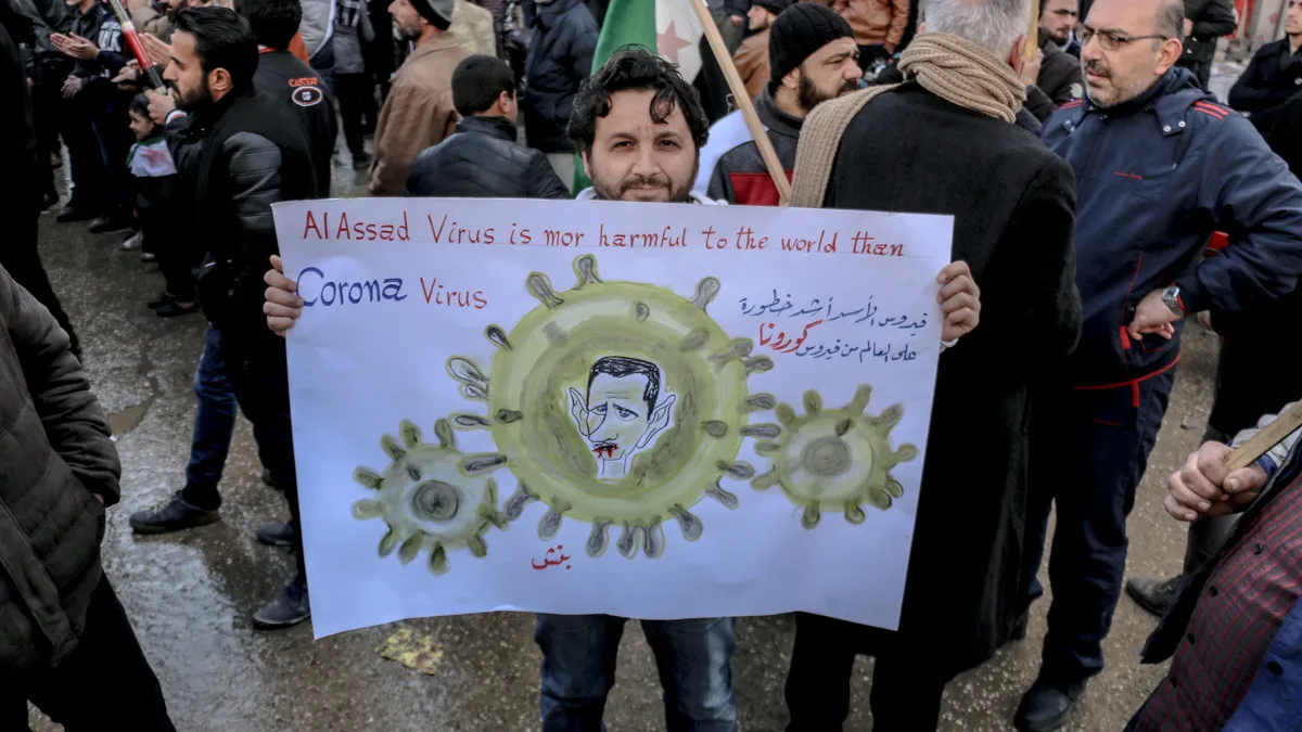 Legislatures: High angle of ethnic male activist with poster standing on crowded street at demonstration against policy.