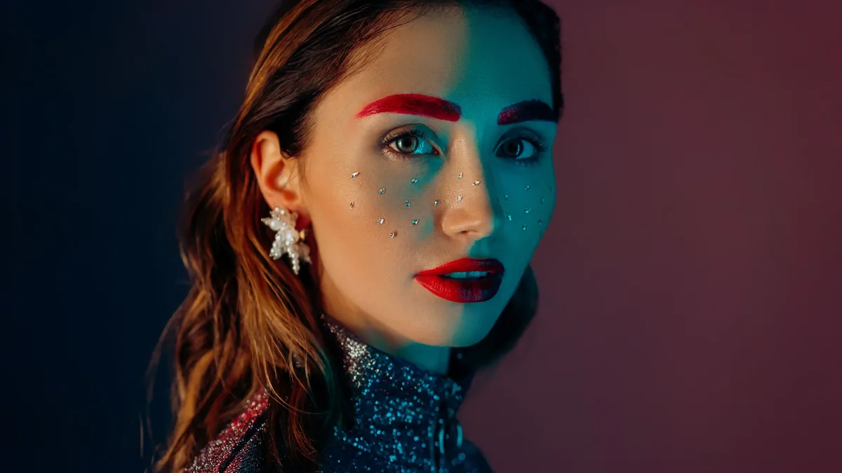 Face: A striking portrait of a woman with vibrant makeup, glitter, and jewels, showcasing fashion and beauty creativity.