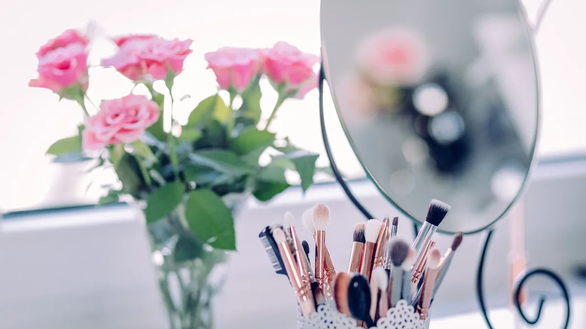 A collection of makeup brushes is neatly arranged in a white container with black polka dots, accompanied by a mirror and a