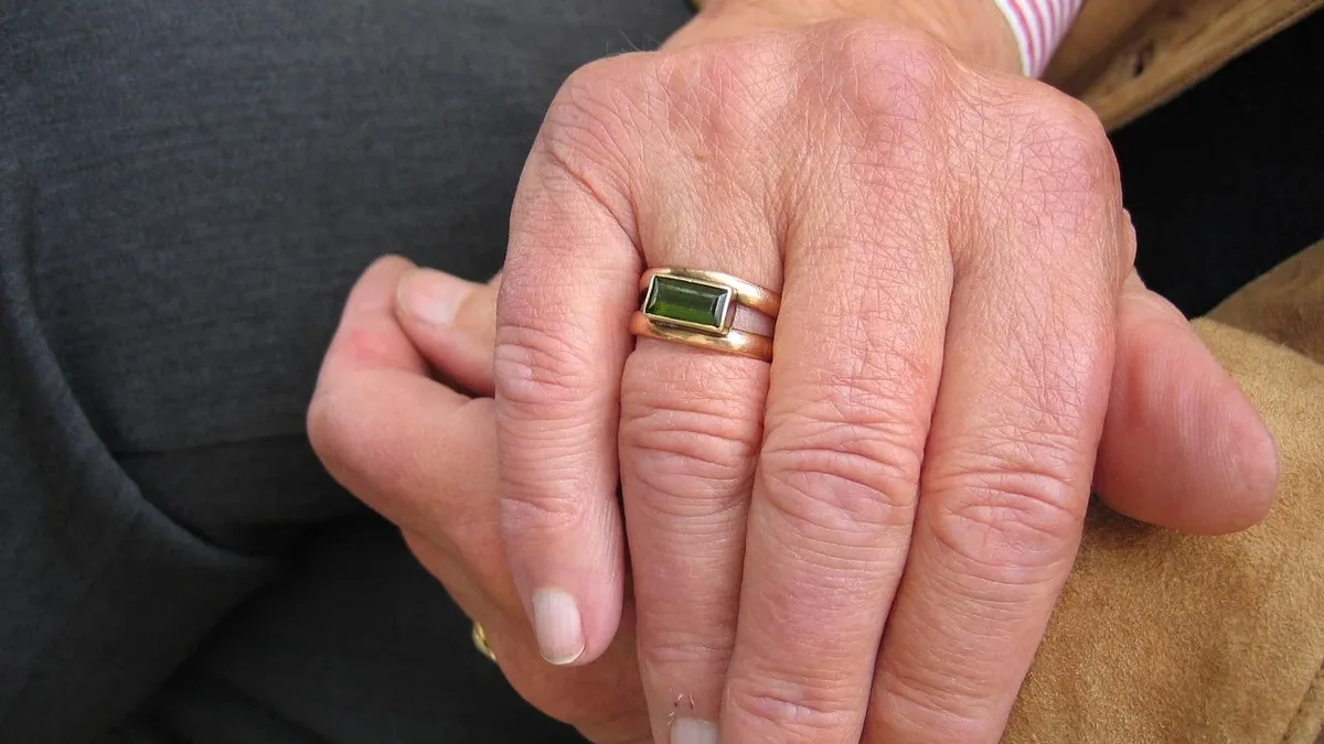 Food Feeding: A person's hand resting on their knee, with a ring on their finger.