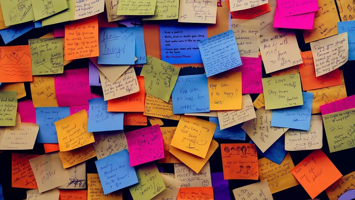 The Scene: A collection of multicolored sticky notes with handwritten text, scattered across a dark surface.
