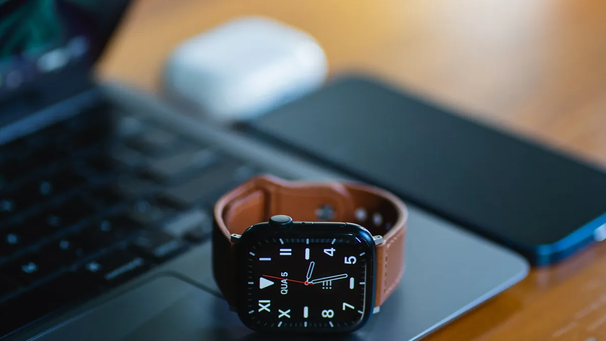 Bags: A smart watch with leather strap resting on a laptop, accompanied by mobile devices, showcasing modern technology