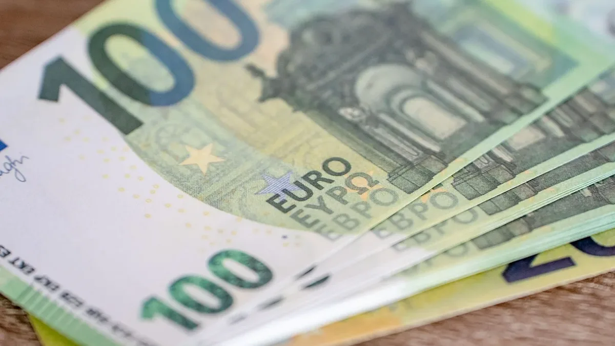 Getting Started: A stack of 100 Euro bills on a wooden surface.