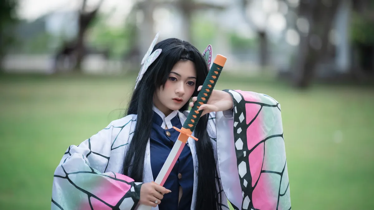 Source Material: Cosplayer dressed as a character holding a sword in a park setting.
