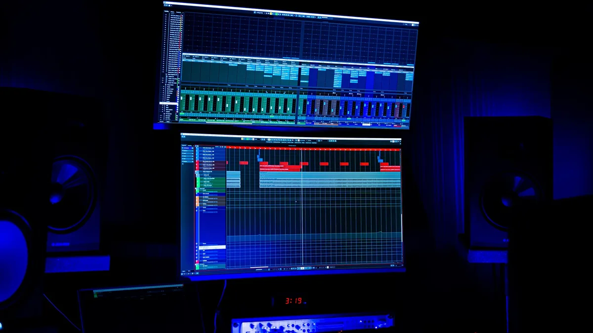 Source Material: A modern recording studio featuring two screens displaying audio editing software under blue neon lighting.