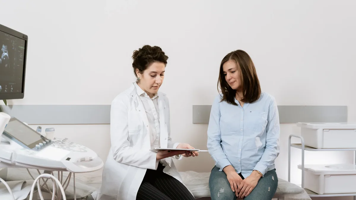 Care Systems: A pregnant woman consulting with a gynecologist in a medical facility.
