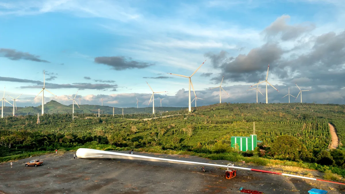 Eu Policy: Vibrant wind farm scene with turbines, equipment, and lush landscape under a blue sky.