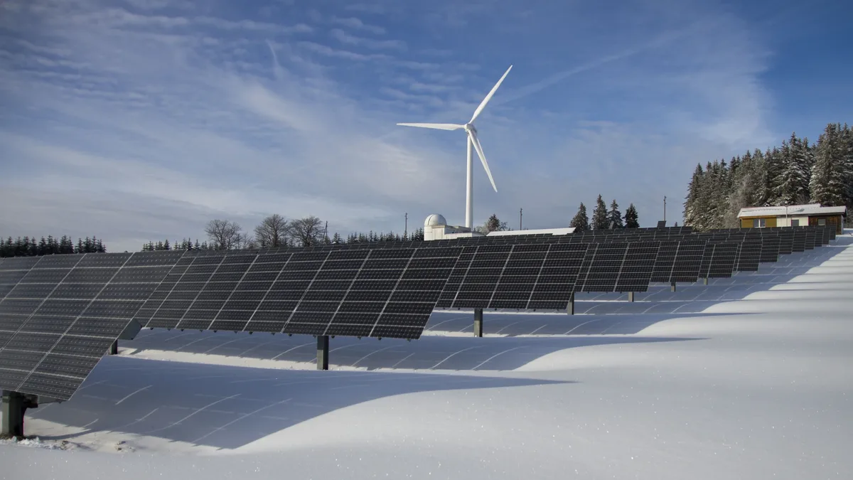 Eu Policy: Solar panels and wind turbine in a snowy landscape, showcasing renewable energy sources.