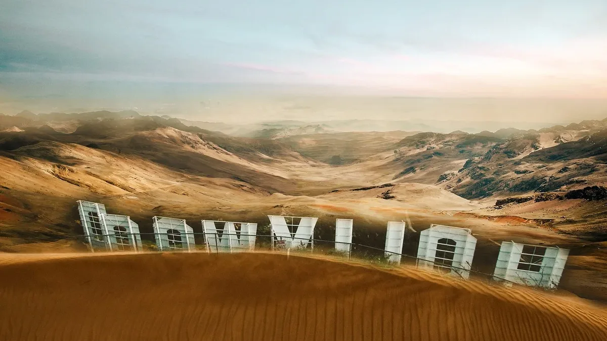 A desert landscape with a row of white letters spelling out "HAWAII" in the foreground, set against a backdrop of rolling