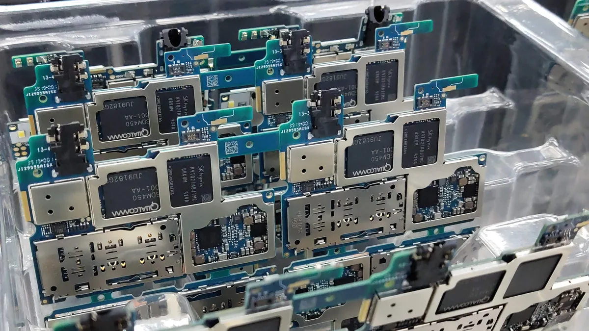 A clear plastic container filled with a collection of small, rectangular computer chips, each featuring a black square in