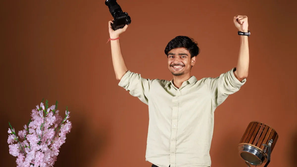 Stages: A joyful young photographer triumphantly raises a camera in a studio setting.