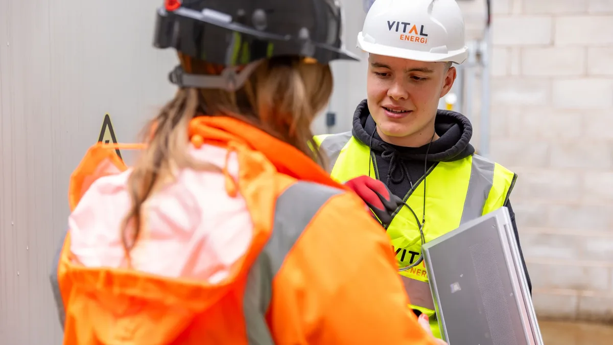 Generation: Two construction workers in safety gear collaborate on a project outdoors.