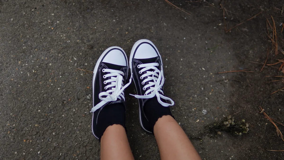 Releases: Black sneakers worn on pavement outdoors, showcasing casual style footwear. Sneakers & Footwear Fashion