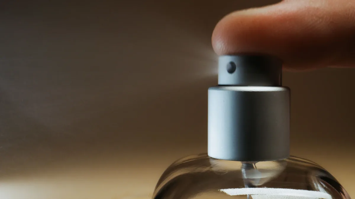 Notes: Detailed shot capturing finger pressing a perfume spray bottle, illustrating a moment of action.