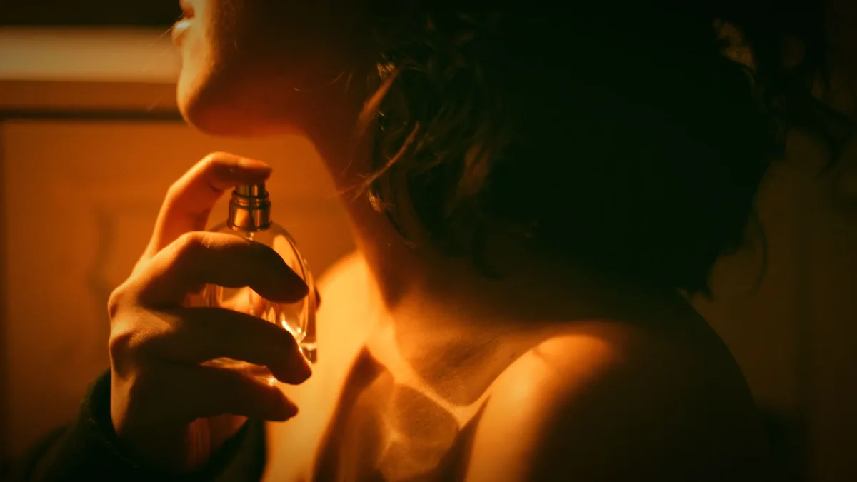 Families: Artistic close-up of a woman applying perfume with warm lighting.