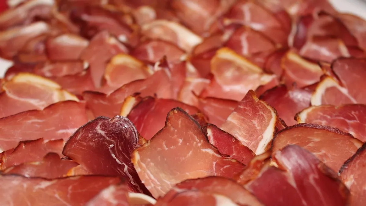 News: A close-up of a large pile of sliced cured meat, likely prosciutto or ham.