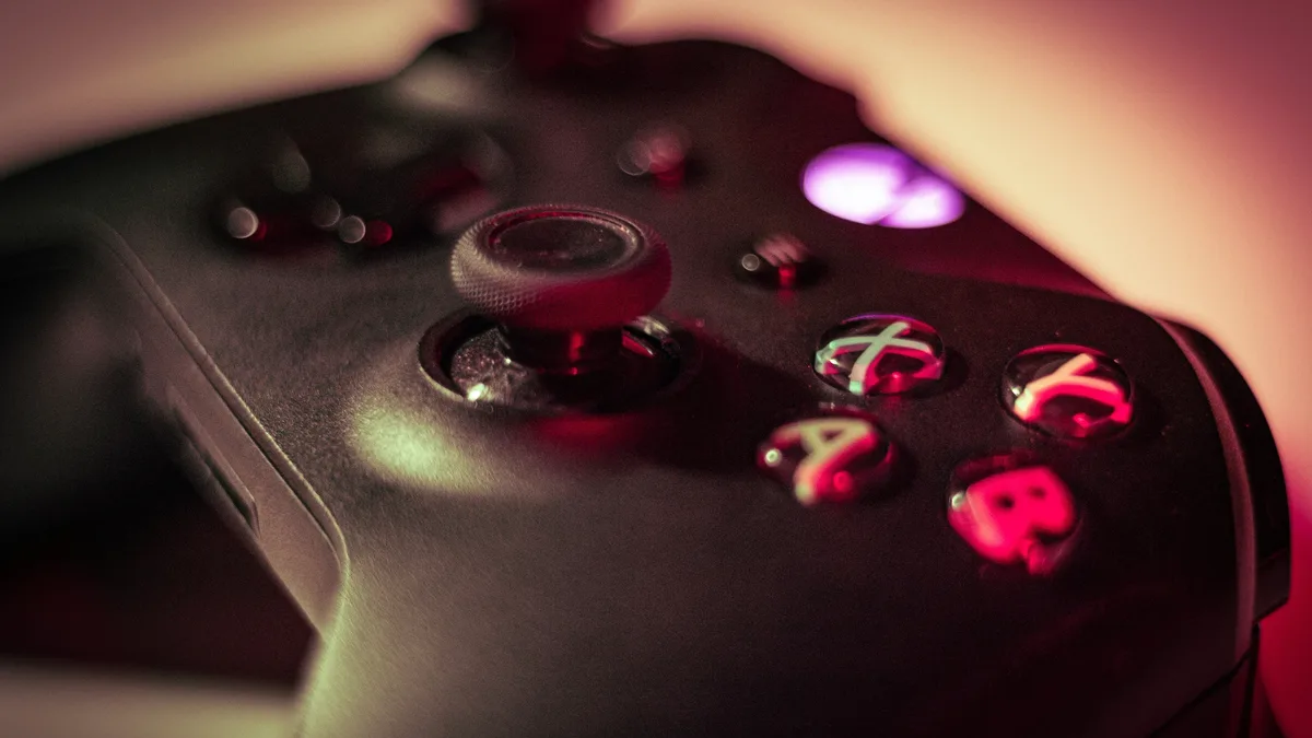 A close-up of a gamer's hands holding a sleek, limited edition green see-through Xbox Series X controller, with a faint...