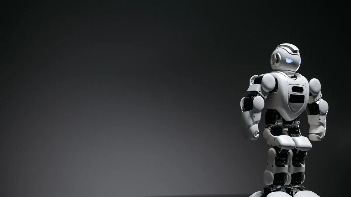 Building With Ai: Compact humanoid robot toy standing on a reflective surface, exuding a futuristic vibe.
