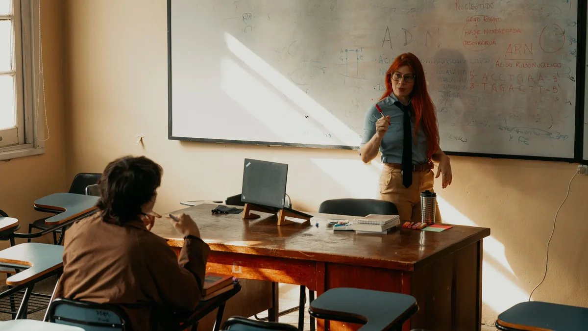 Student Life: A teacher conducts a lesson in a sunny Buenos Aires classroom, engaging with a student.