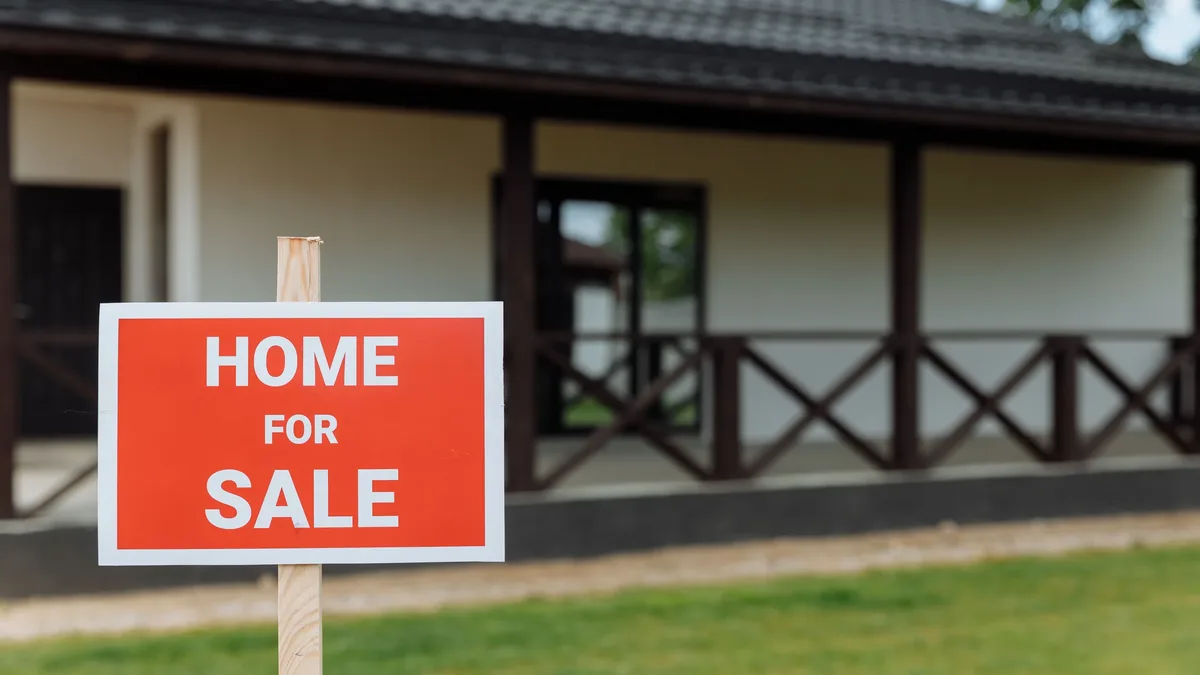 Alquilar: A red "HOME FOR SALE" sign in front of a house.