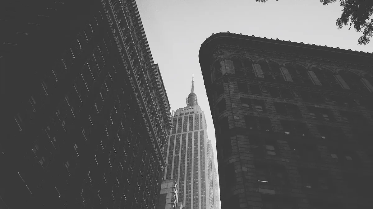 The Empire State Building, a tall skyscraper with a distinctive Art Deco design, situated between two other buildings, with