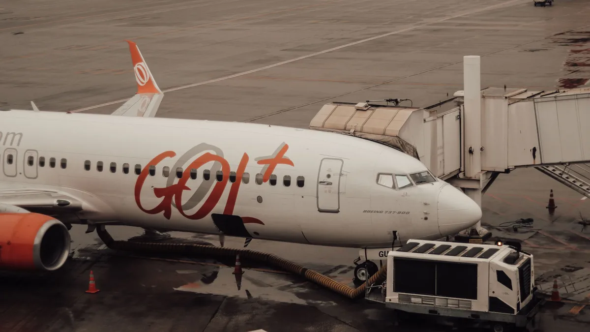 Air Traffic Control: GOL Airlines aircraft connected to jet bridge at a wet airport terminal.