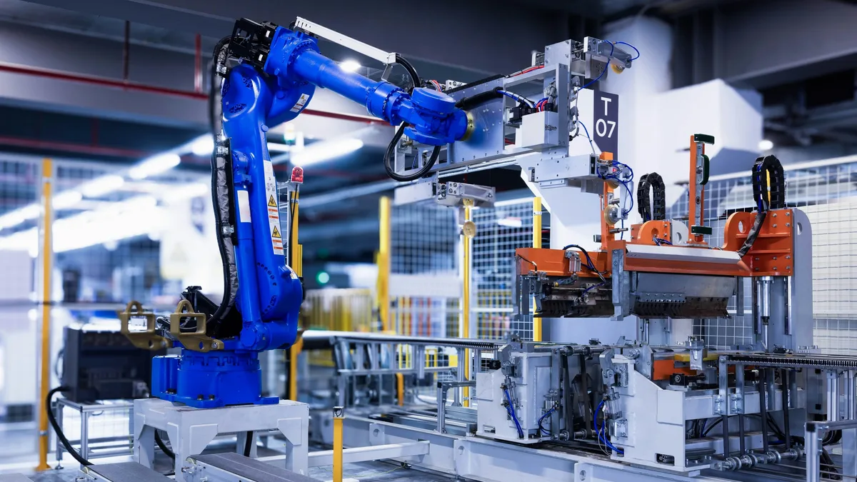 Automation: A large blue robotic arm situated in a factory setting, with a metal frame and a white wall in the background.