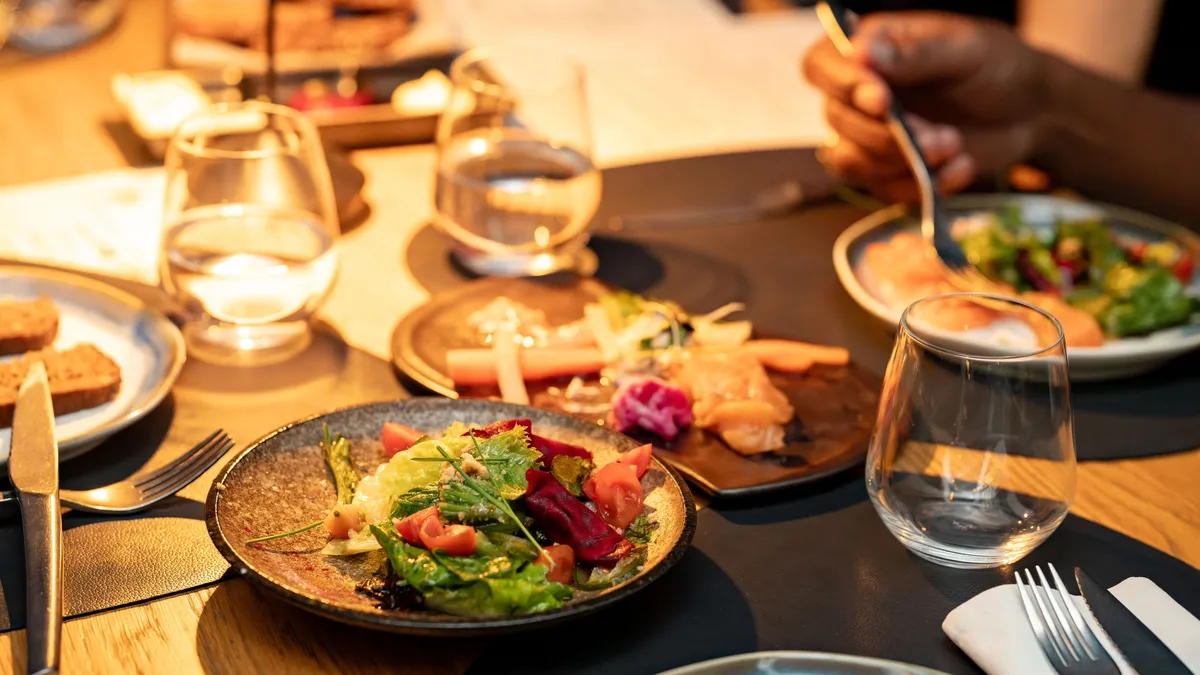A beautifully set dinner table with gourmet salads and glassware, ideal for a classy dining experience. Restaurants & Dining
