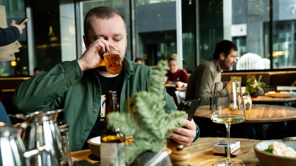 The Business: Man enjoying beer at a modern city cafe with friends and technology. Restaurants & Dining technology