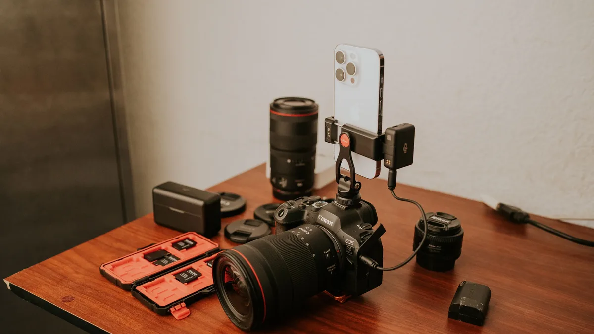 Juegos: Close-up of professional camera gear including a and smartphone on a wooden table.