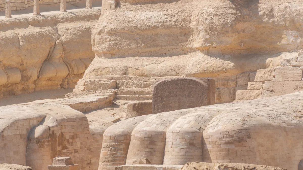 Regions Periods: Close-up of the ancient Sphinx and surrounding stone structures in Giza captured in detail.