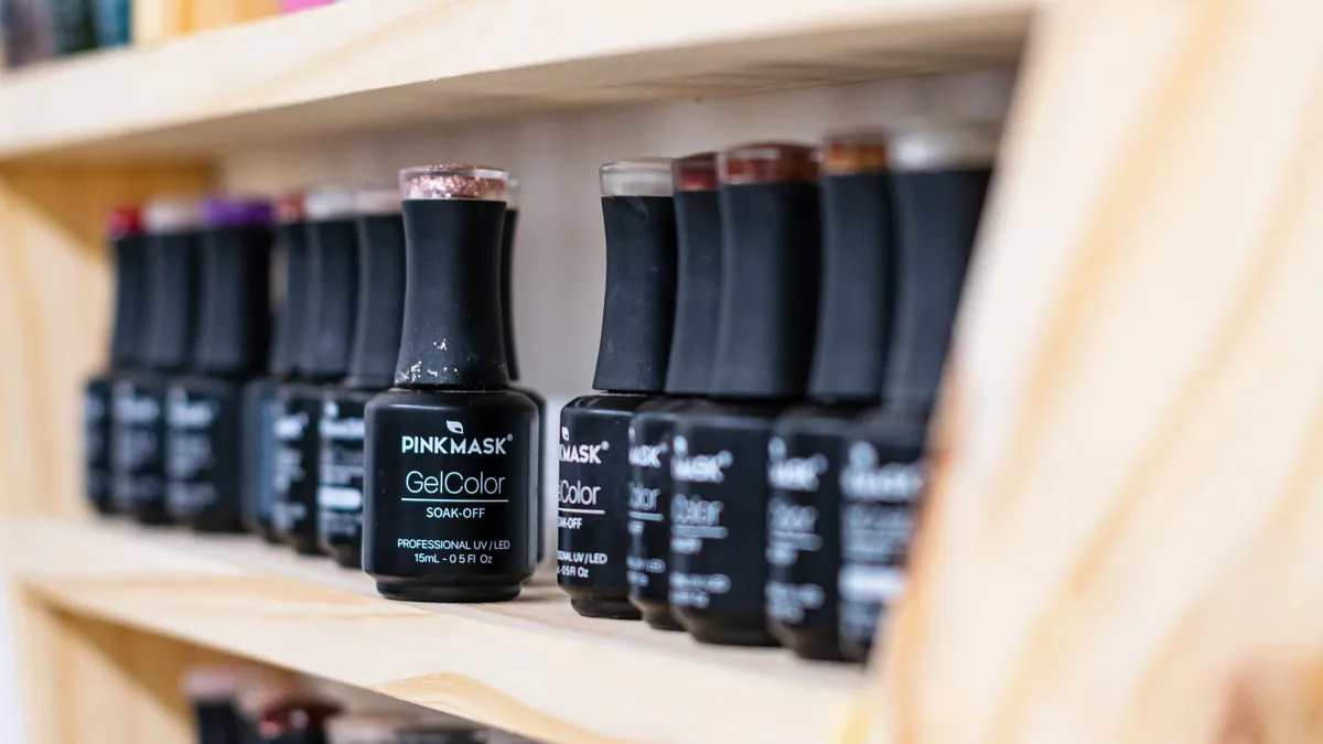 Nail Care: A vibrant collection of gel nail polish bottles neatly organized on a wooden shelf. Nails professional photography