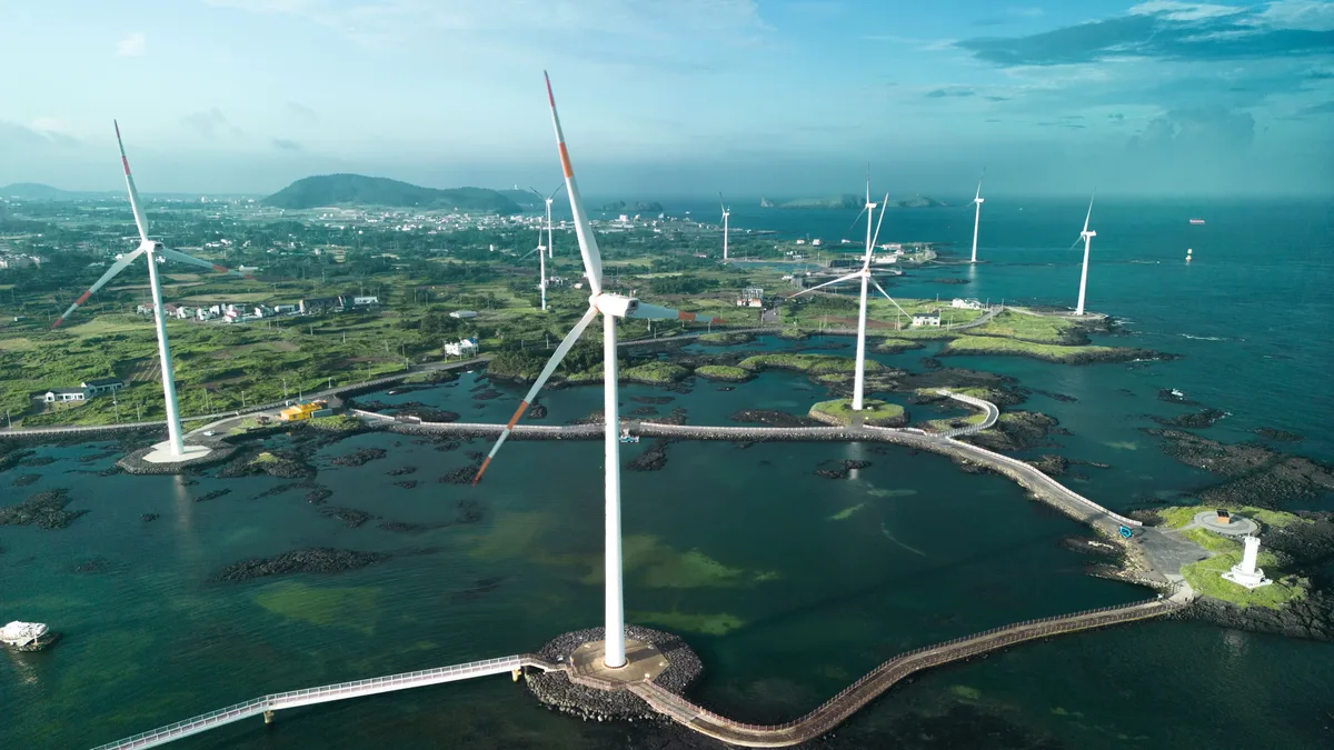 Technologies: Aerial photo of wind turbines set against a coastal landscape with bright blue waters. Renewable Energy