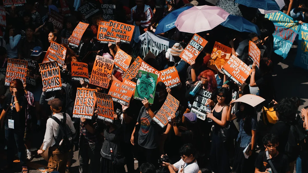 Themes: Crowd gathering with colorful signs demanding human rights and freedom in a peaceful protest. Human Rights