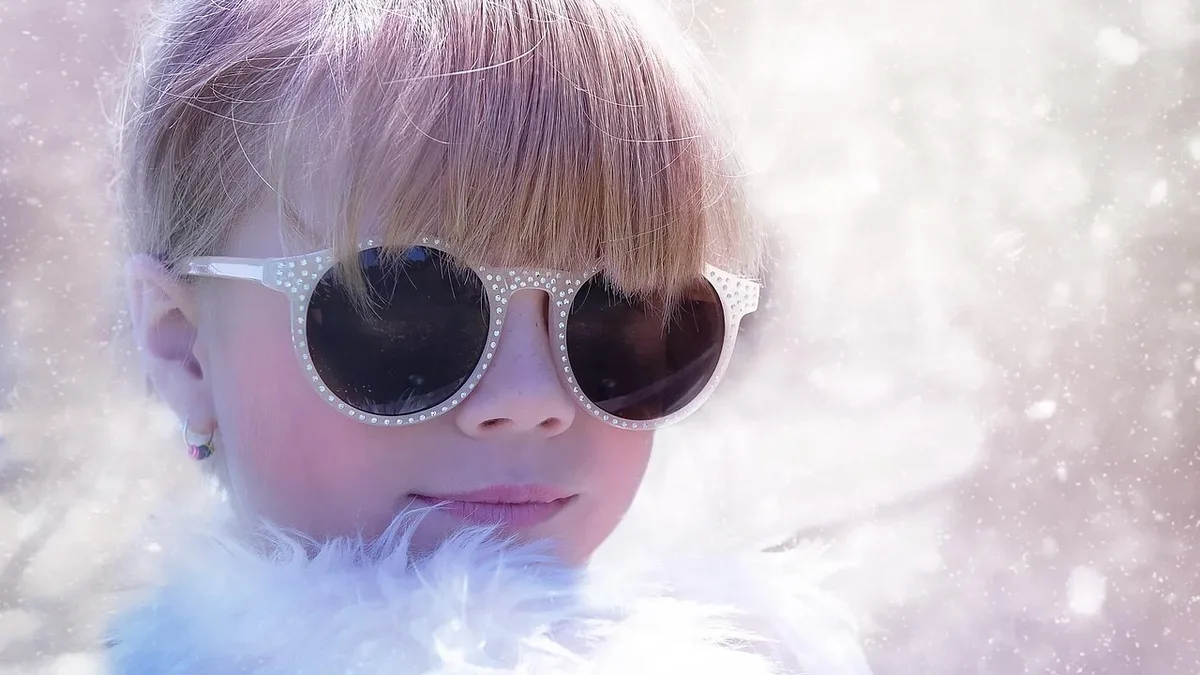 Groups At Risk: A young girl wearing sunglasses and a white fur coat, with a blurred background.