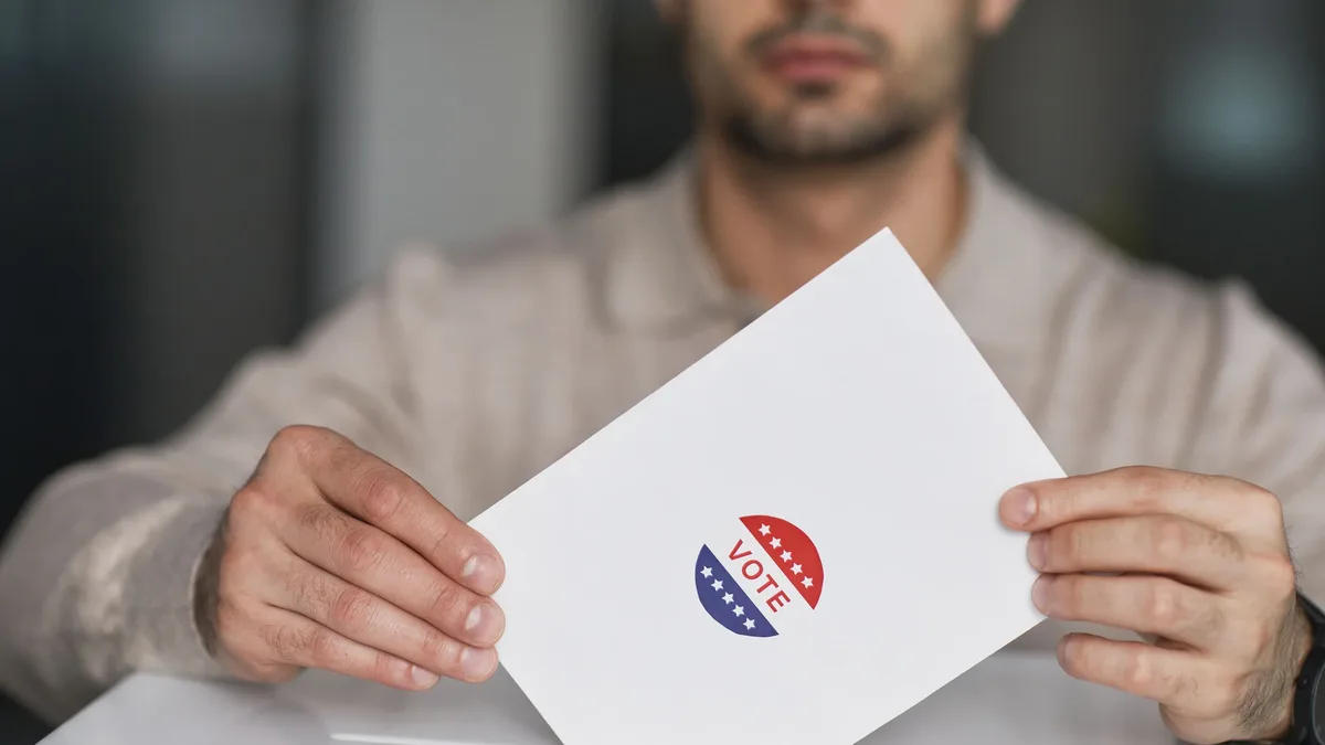Mechanisms: A man holds a voting envelope with a vote sticker.