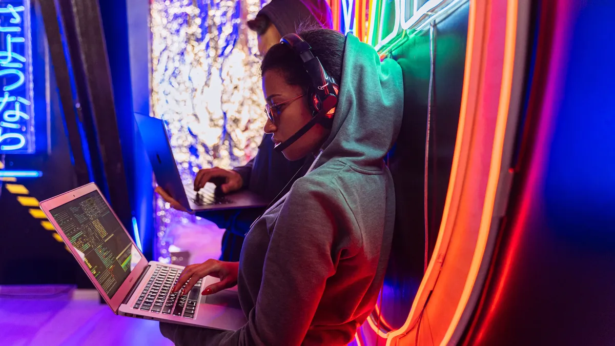 Threats: Team of cyber security experts working on laptops in a vibrant neon-lit room